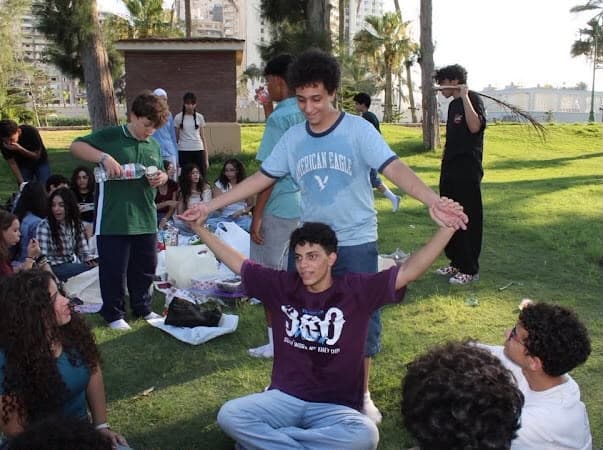 Outdoor club gathering on the grass with palm trees in Alexandria